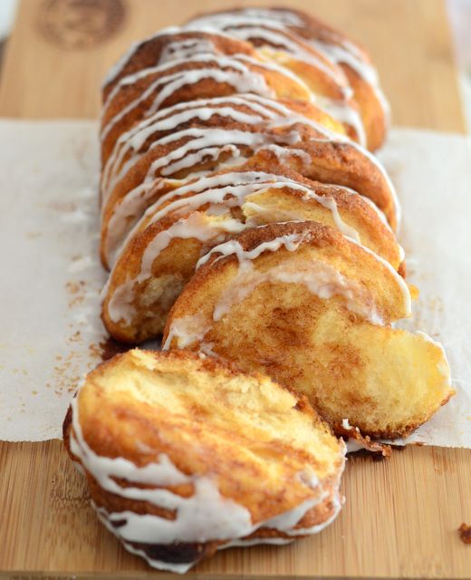 a wooden cutting board topped with donuts covered in icing