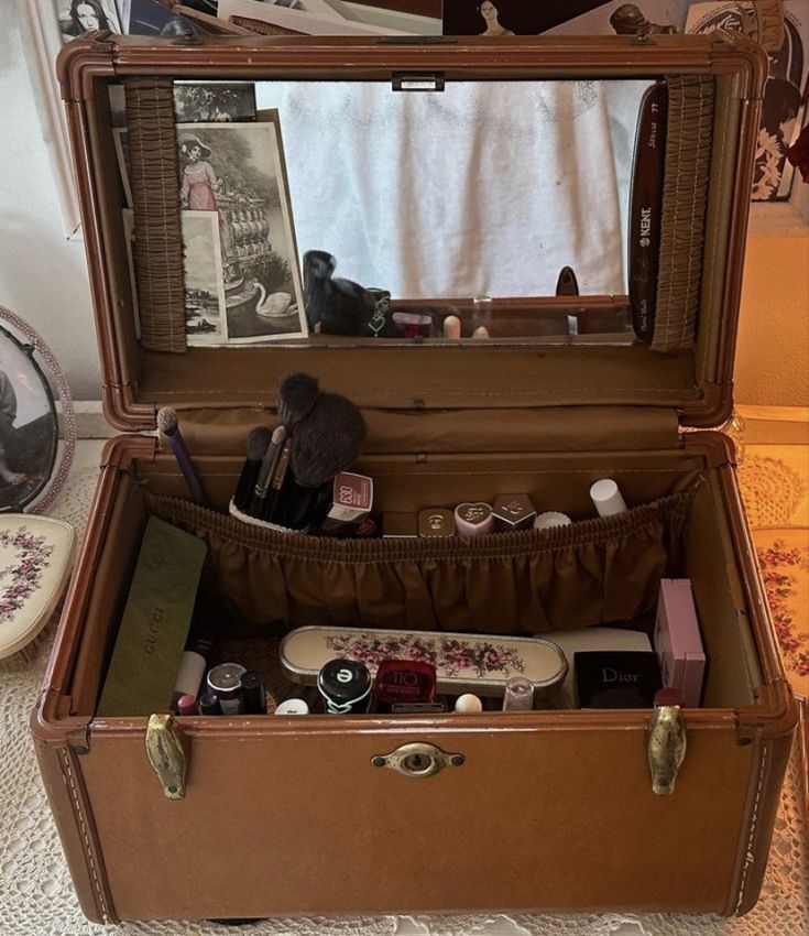 an open suitcase sitting on top of a bed next to a mirror and other items