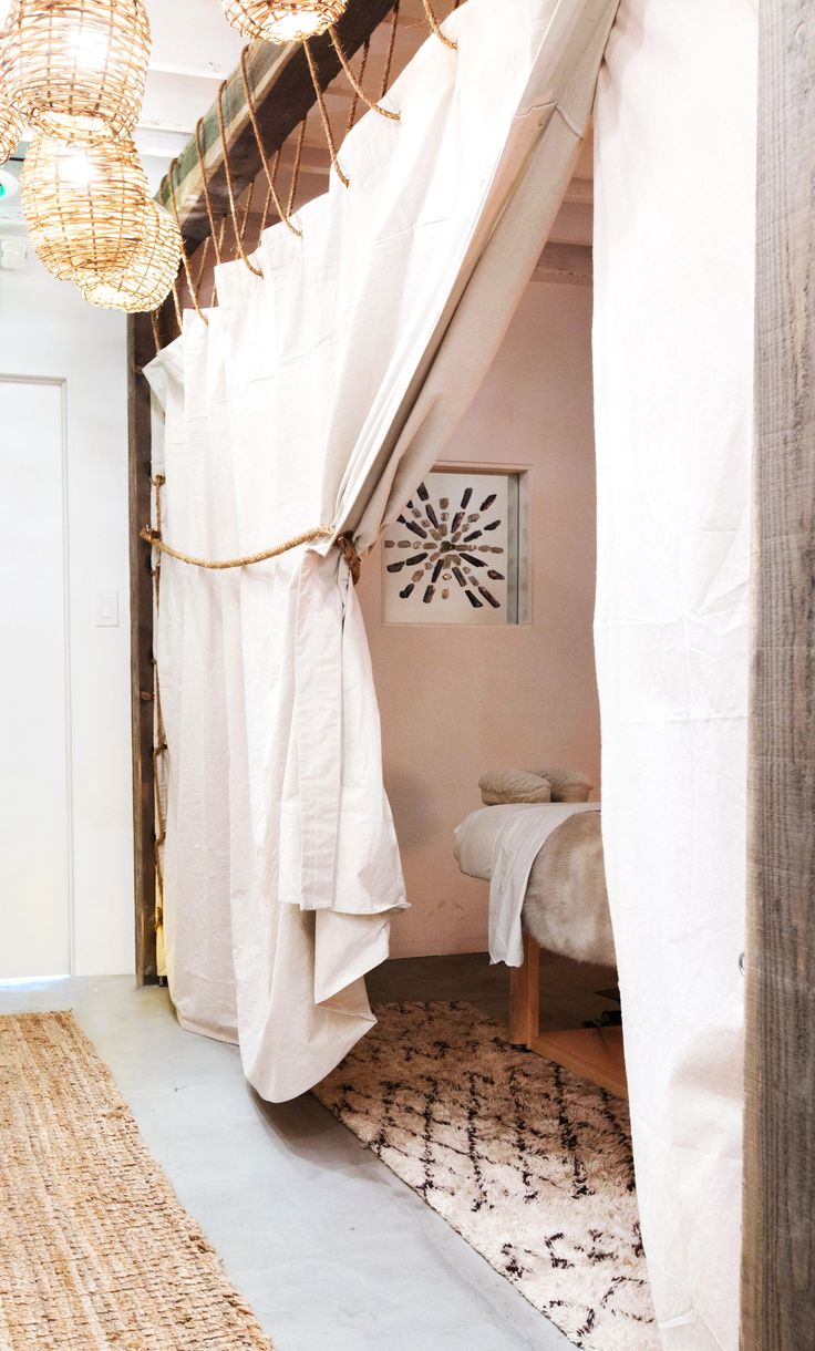 a bedroom with white curtains and lights hanging from the ceiling