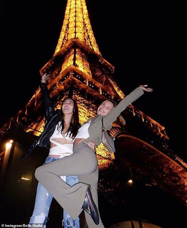 two women are posing in front of the eiffel tower