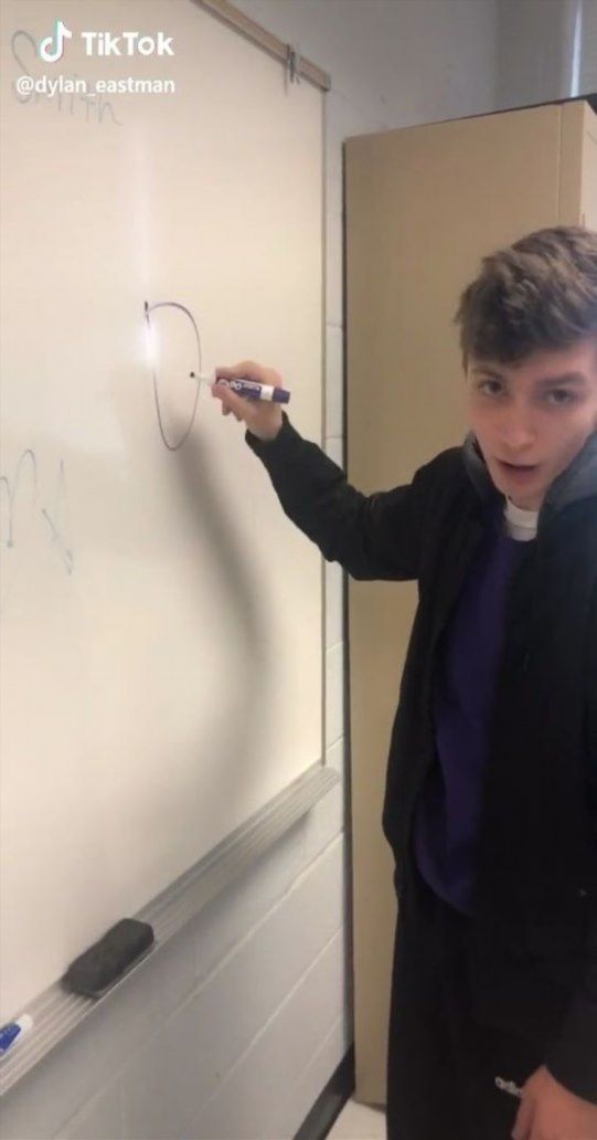 a young man writing on a white board