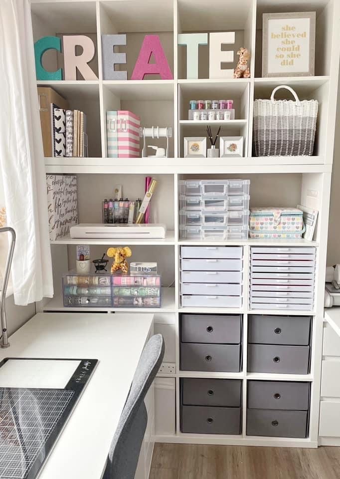 an organized craft room with white shelves and gray bins