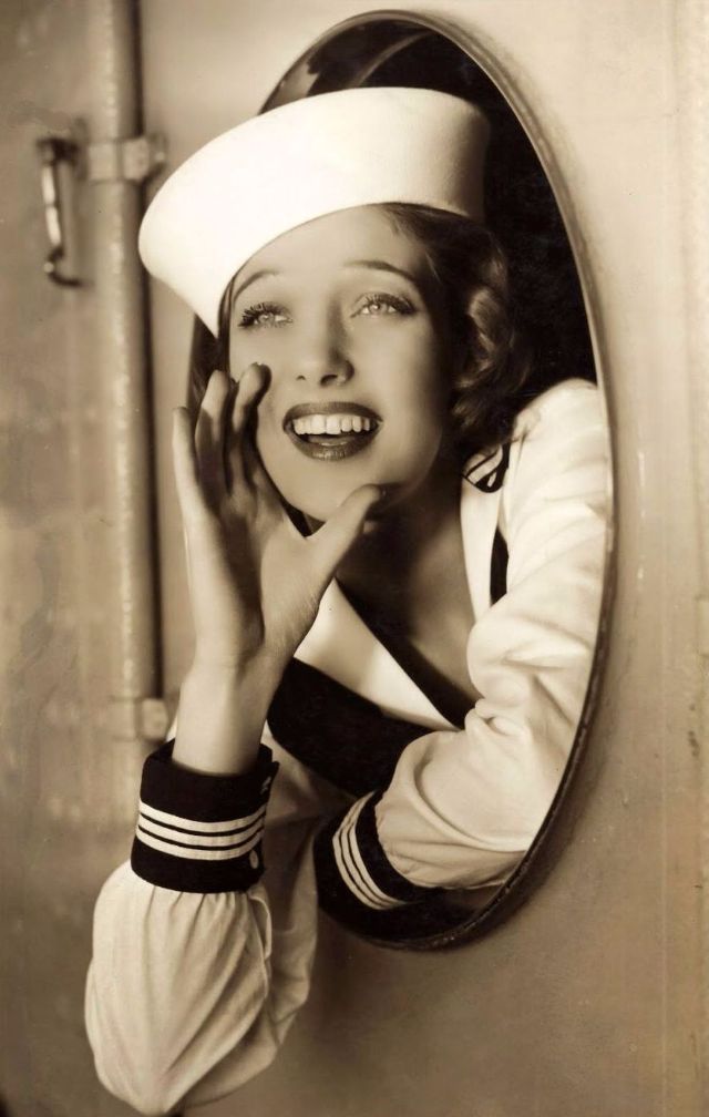 an old photo of a woman wearing a sailor's hat in front of a mirror