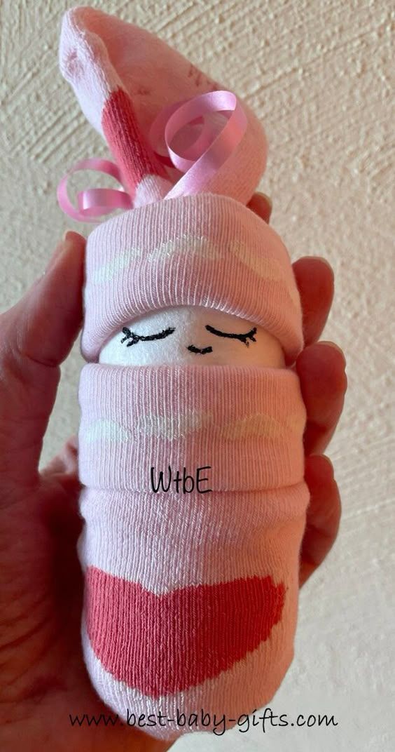 a hand holding a wrapped up doll with the word whe on it's face