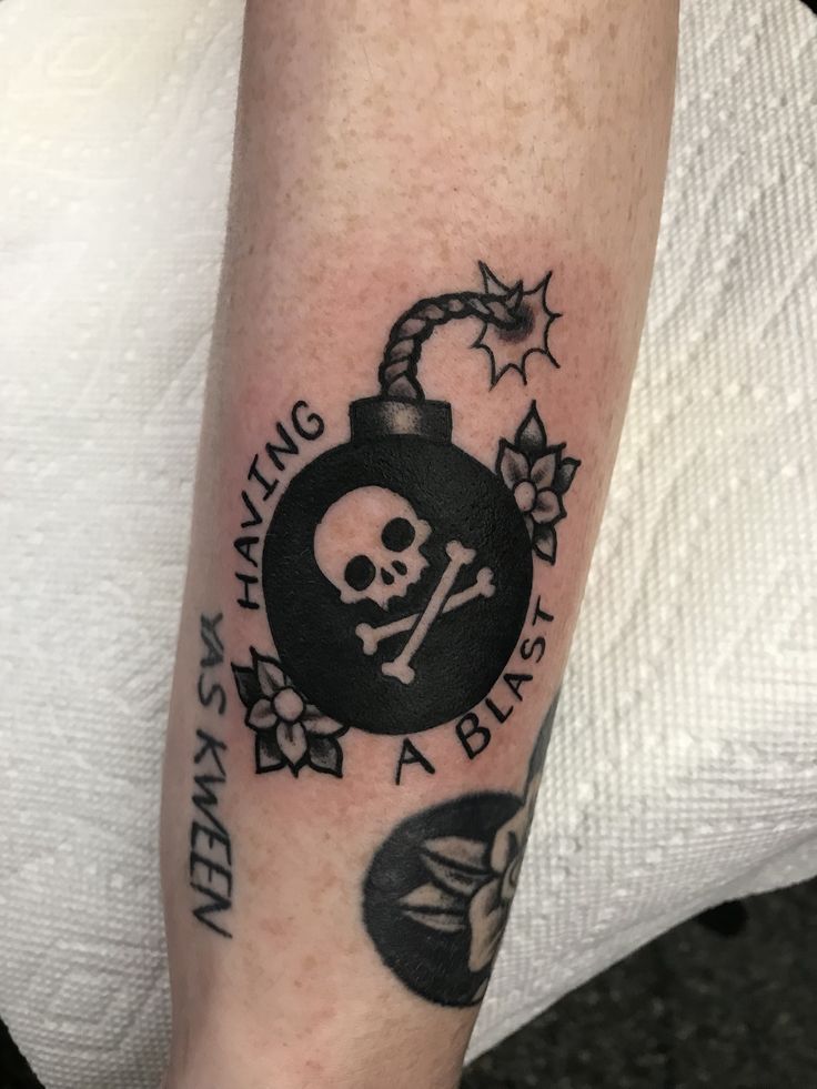 a skull and crossbones tattoo on the arm with words written in black ink