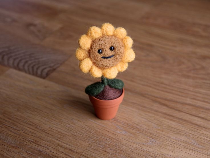 a small felt sunflower sitting on top of a potted plant with a smiling face