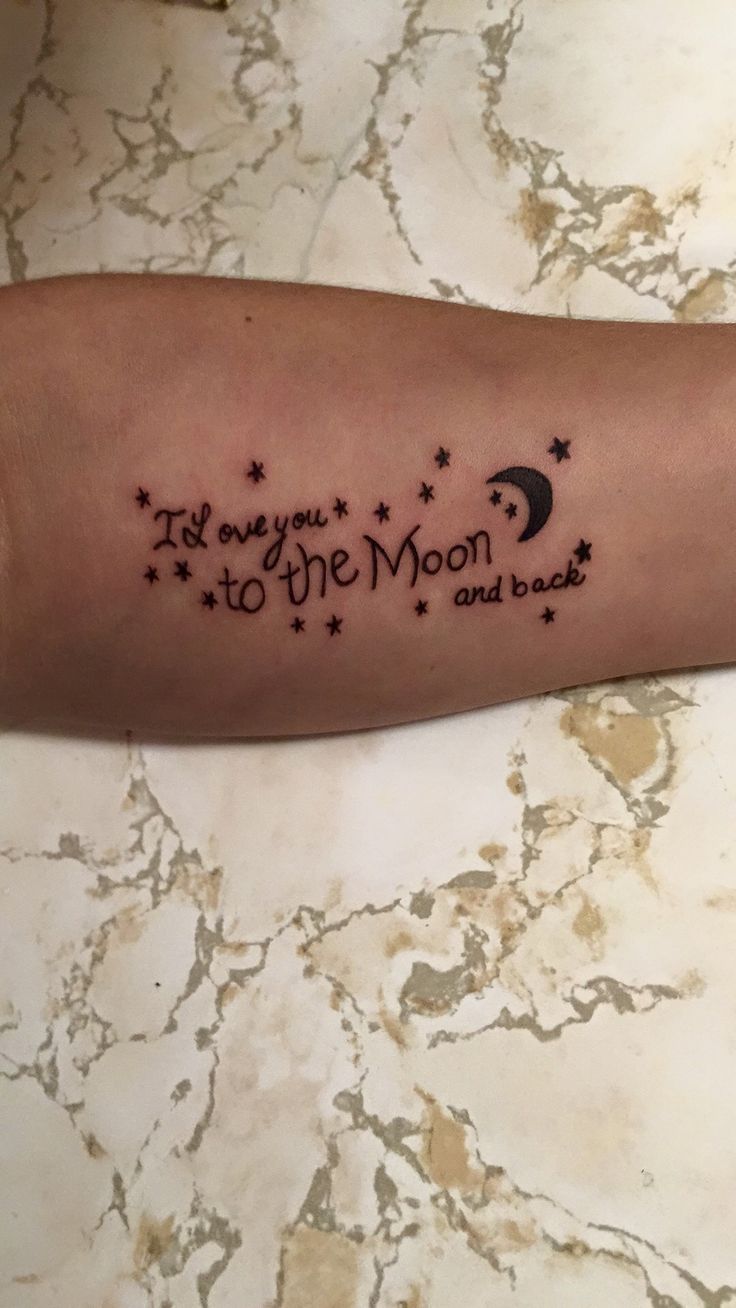 a person with a tattoo on their arm that says i love you to the moon and back