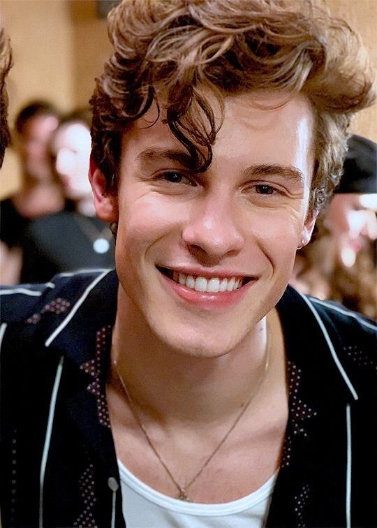 a young man with curly hair smiling at the camera