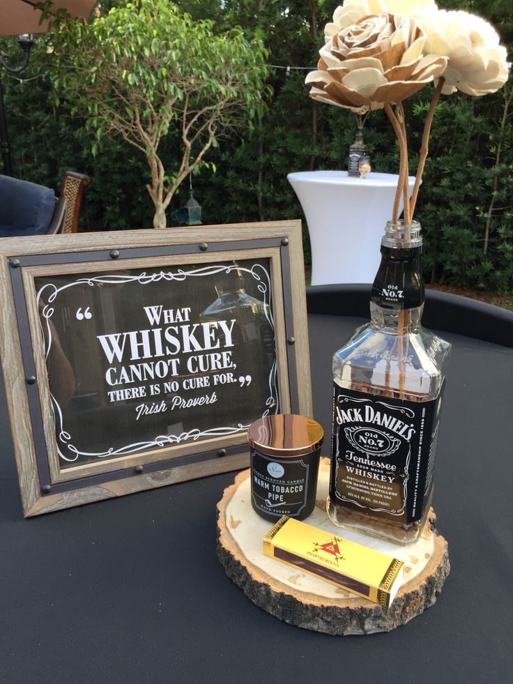 a table topped with a bottle of whiskey next to a sign