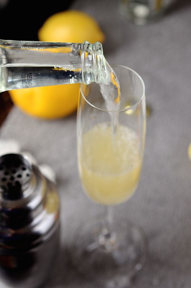 a glass filled with liquid next to lemons