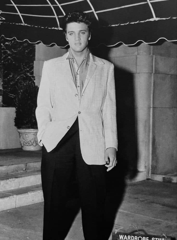 black and white photograph of man in suit standing on steps with his hands in his pockets