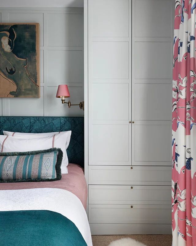 a bedroom with pink and blue bedding, white cabinets and a painting on the wall