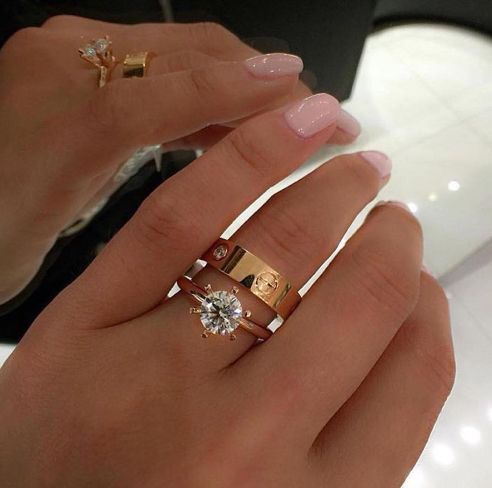 a woman's hand with two rings on it and one has a diamond in the middle