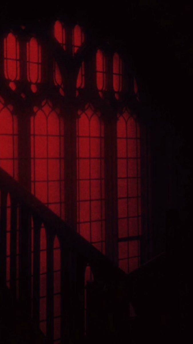 red light shining through the windows in a dark room with stairs leading up to it