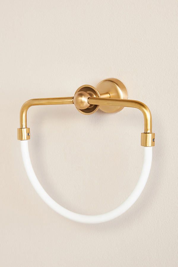 a gold and white bathroom light on a wall with a circular glass holder in the middle