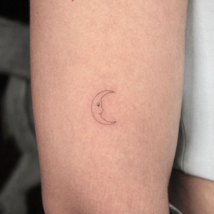 a woman's arm with a small crescent tattoo on the left side of her thigh