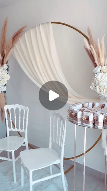 two white chairs sitting next to each other in front of a table with flowers on it