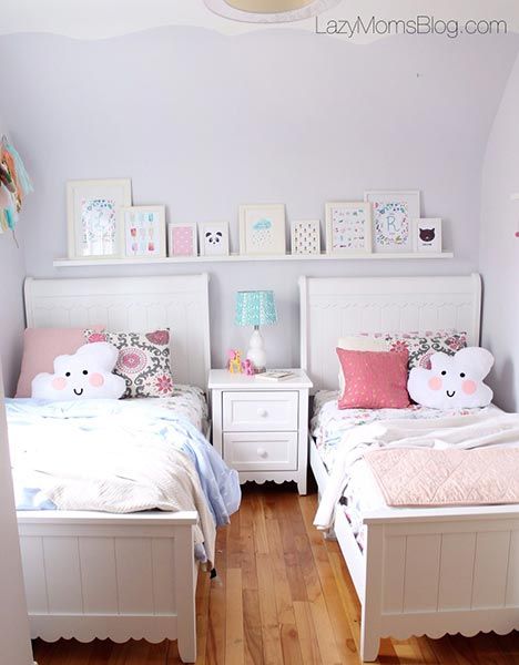 two white twin beds in a bedroom with pink and blue decor on the headboards