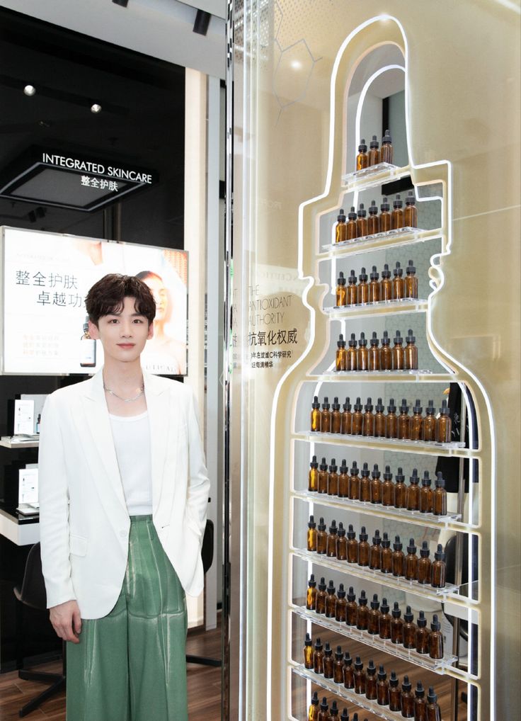 a woman standing in front of a display case with many bottles on the wall and shelves