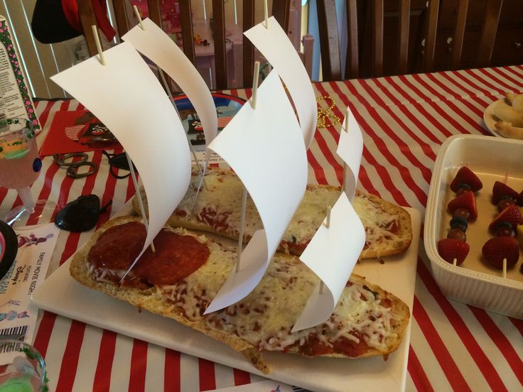 a table topped with slices of pizza covered in cheese and toppings next to a container of strawberries