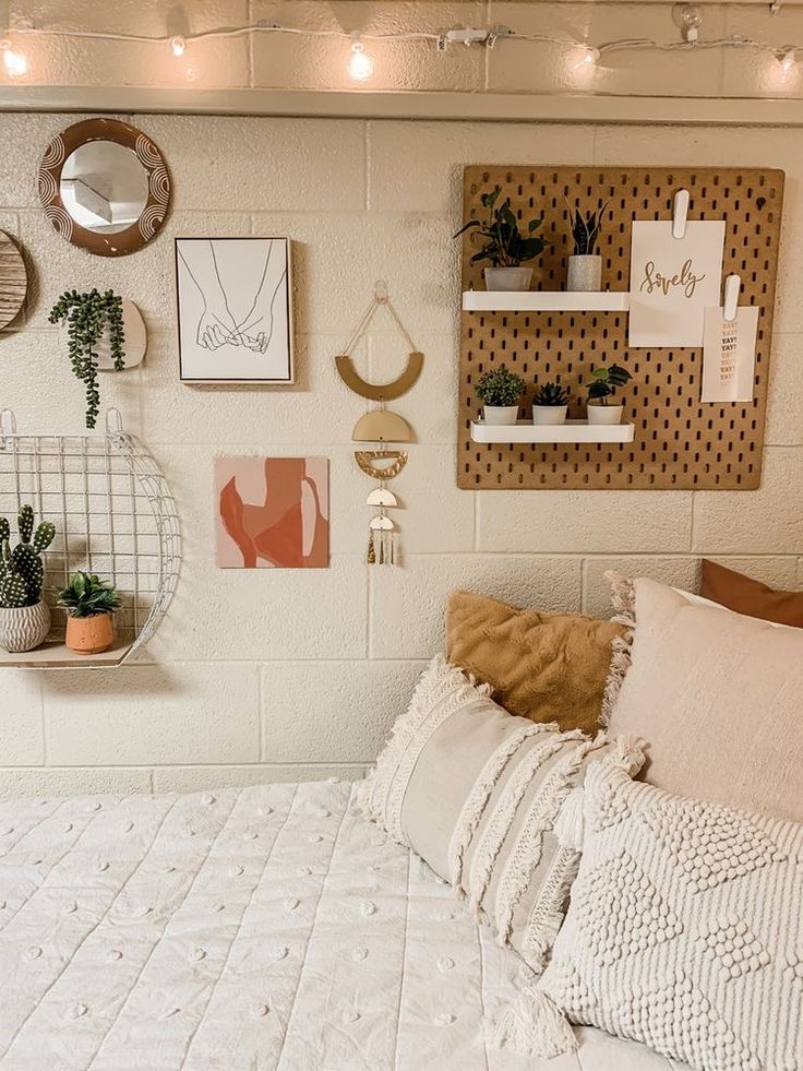 a white bed topped with lots of pillows next to a wall filled with potted plants