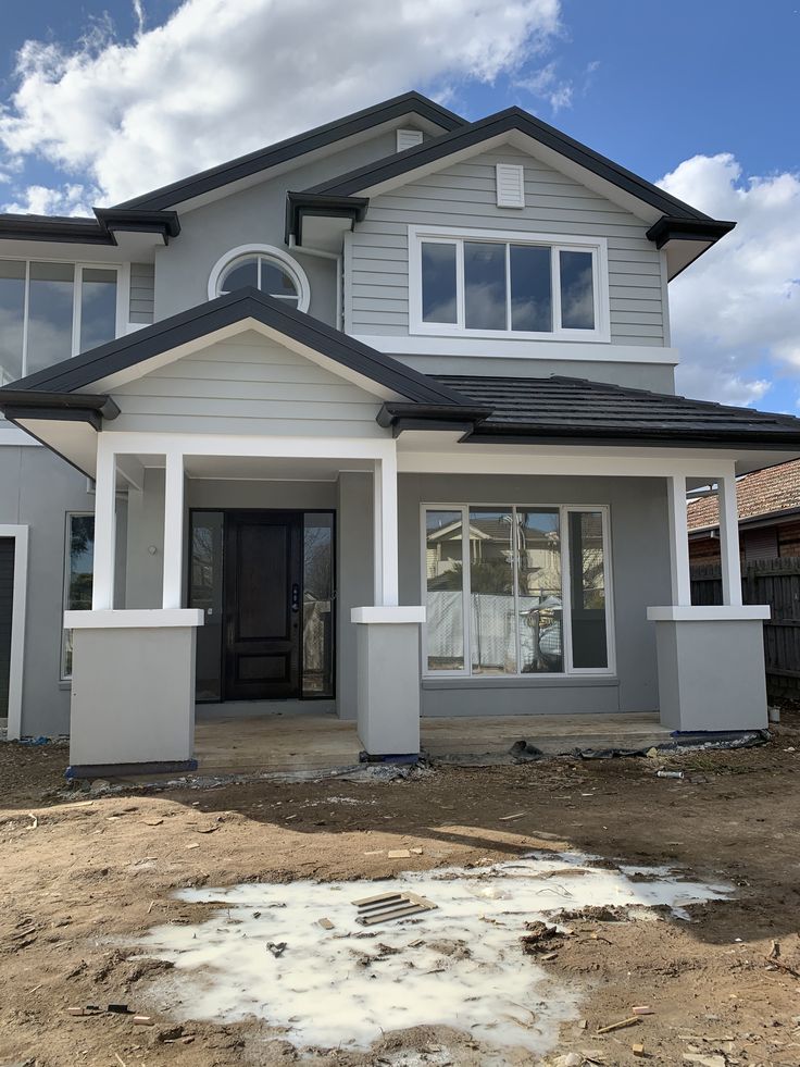 a house under construction with the front door and windows painted white, on a sunny day