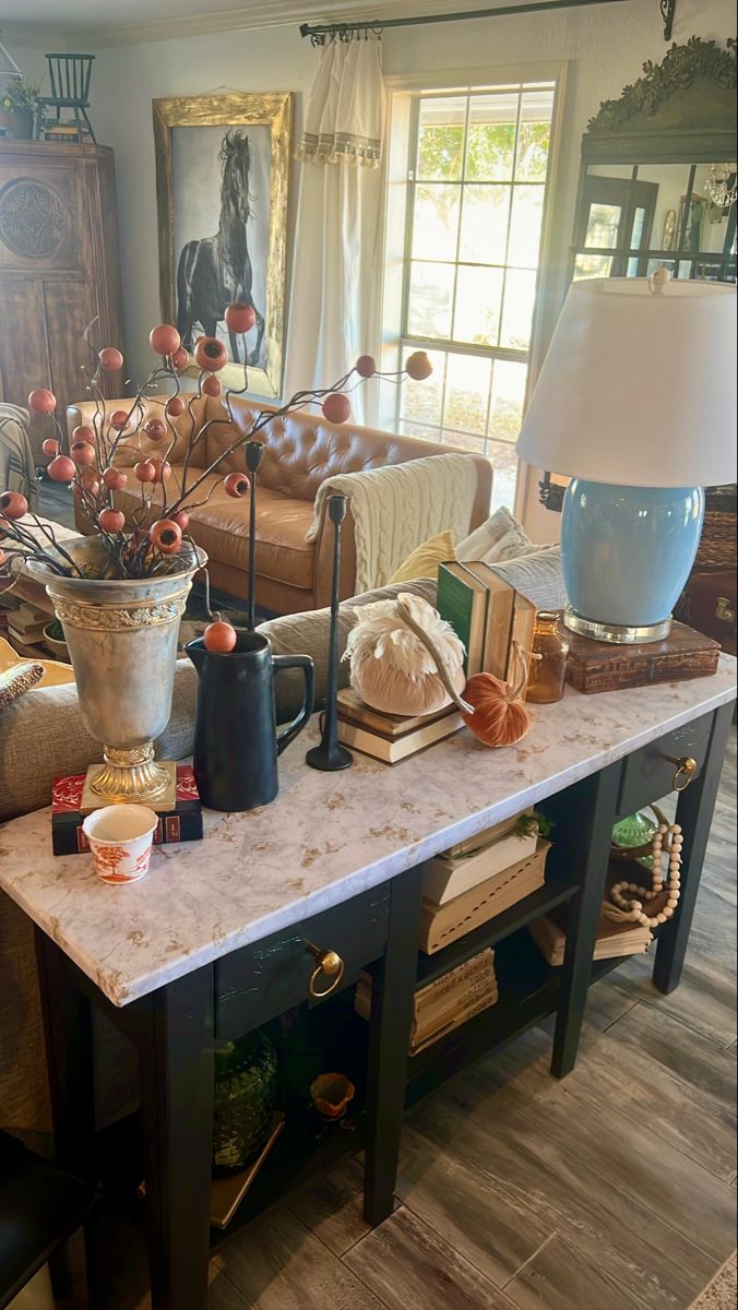 a living room filled with furniture and a table covered in vases on top of it