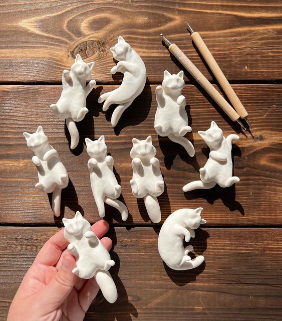 a hand holding a small white cat figurine on top of a wooden table