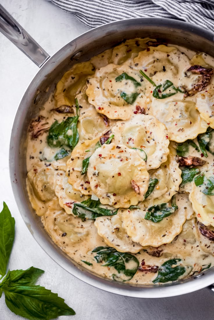 a pot filled with pasta and spinach on top of a table