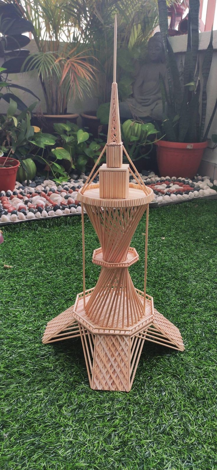 a small wooden structure sitting on top of green grass next to potted plants and rocks