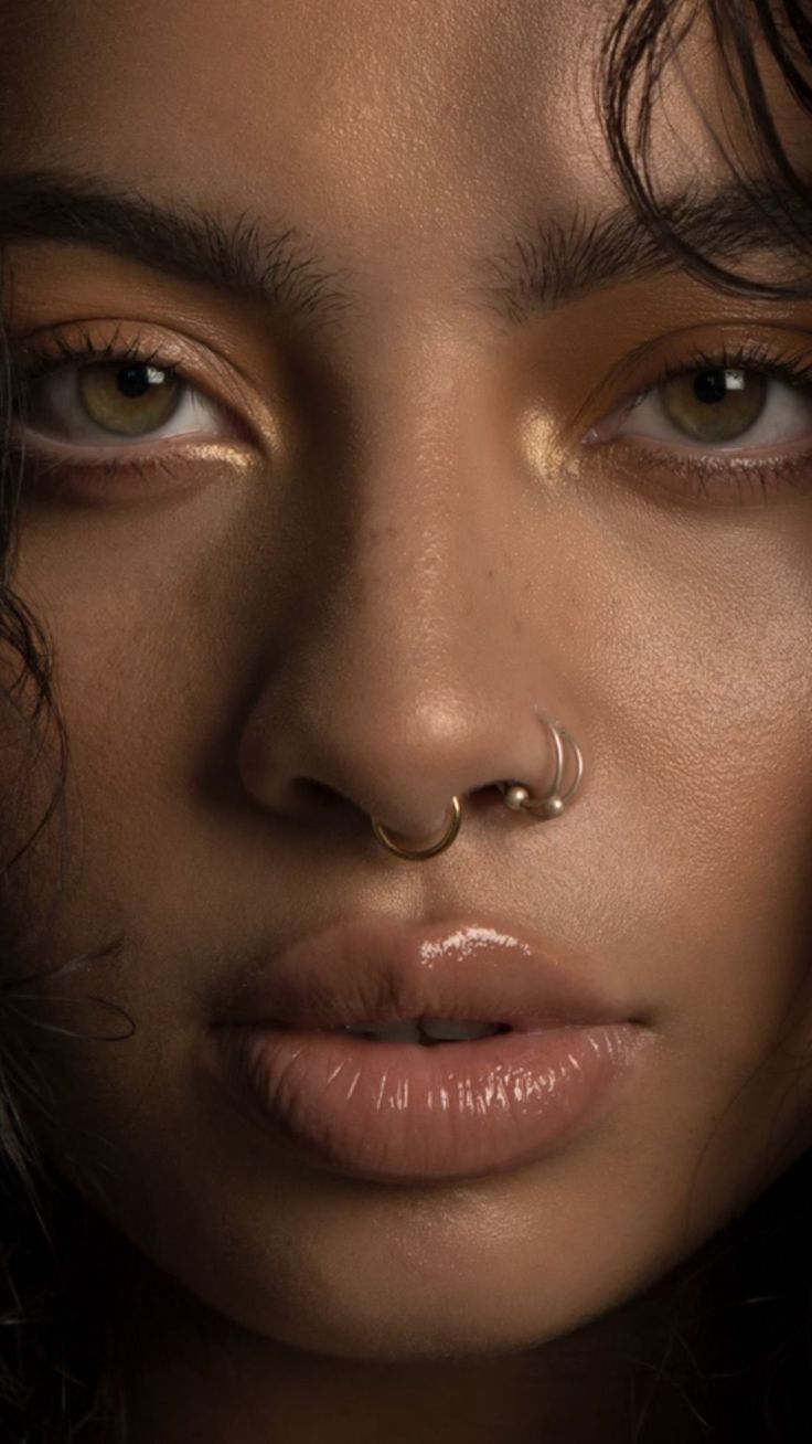 a woman with piercings on her nose and nose ring in front of her face