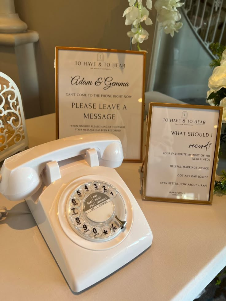 A white rotary telephone used as an audio guestbook at a wedding with two photo frames with instructions on how to use the guestbook. Voice Mail Wedding Guest Book, Voice Recording Wedding Guest Book, Wedding Voicemail, Audio Guest Book Table, Wedding Telephone, Roaring 20s Wedding Theme, 20s Wedding Theme, Wedding Seating Chart Display, Seating Chart Display