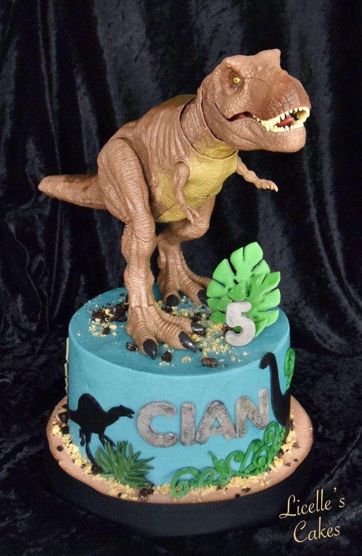 a dinosaur birthday cake with blue icing and gold sprinkles