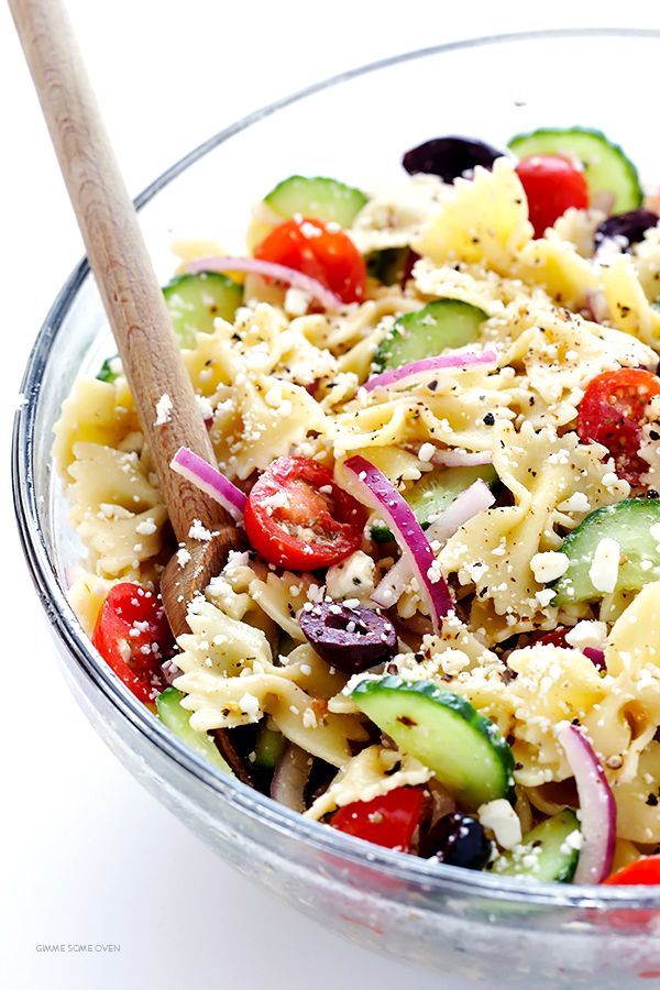 a pasta salad with cucumbers, tomatoes, olives and parmesan cheese