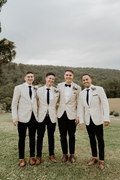 three men in suits standing next to each other on a grass covered field with trees