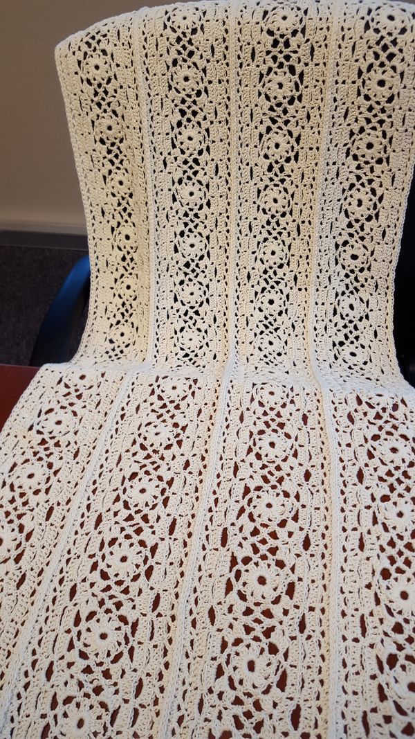 a white crocheted blanket sitting on top of a chair