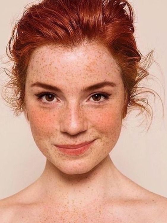 a woman with freckles on her face and red hair smiling at the camera