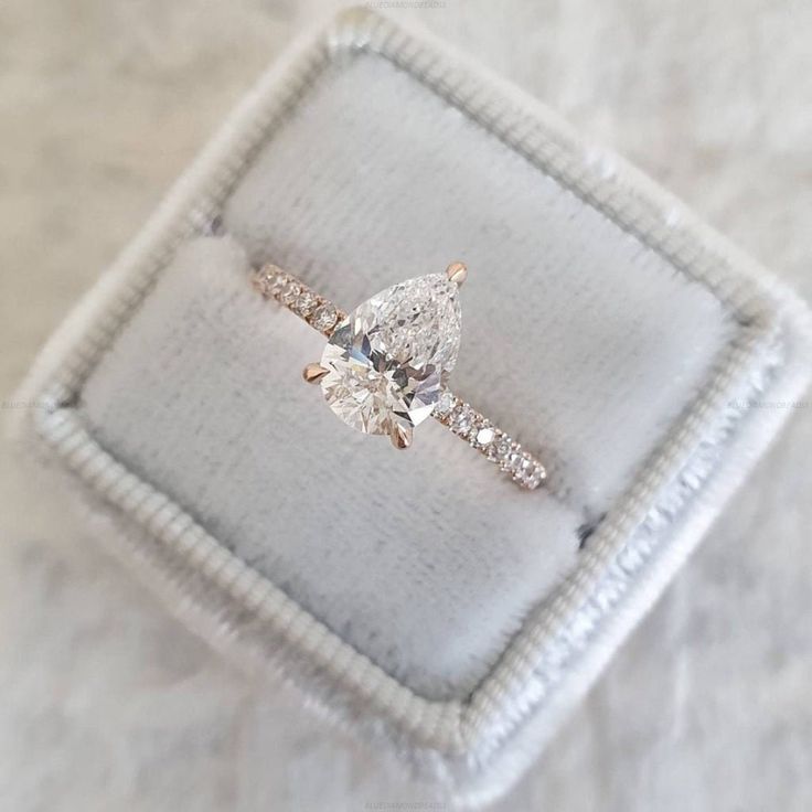 a diamond ring sitting on top of a white cloth covered cushioned surface in a box