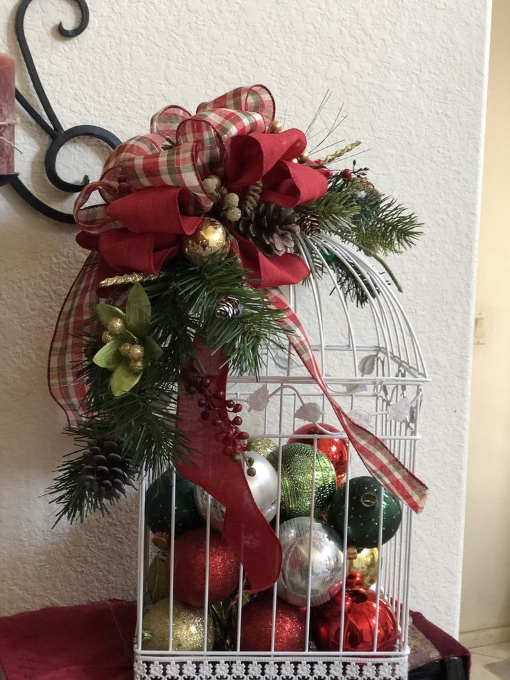 a birdcage filled with christmas ornaments on top of a table