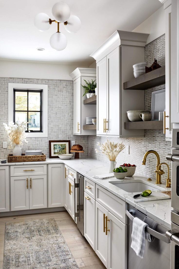 the kitchen is clean and ready for us to use it's white cabinets, marble counter tops, and gold pulls