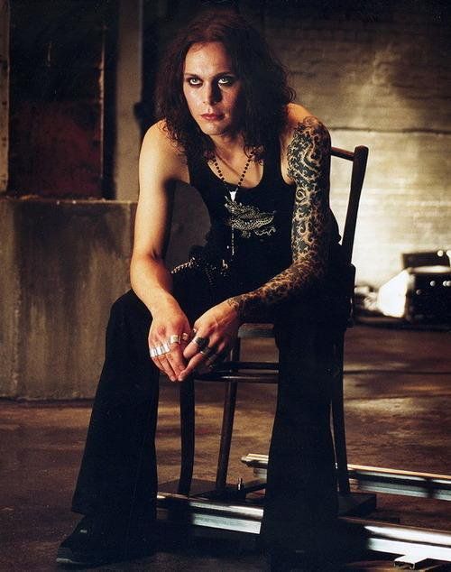 a woman sitting in a chair with tattoos on her arm and leg, posing for the camera