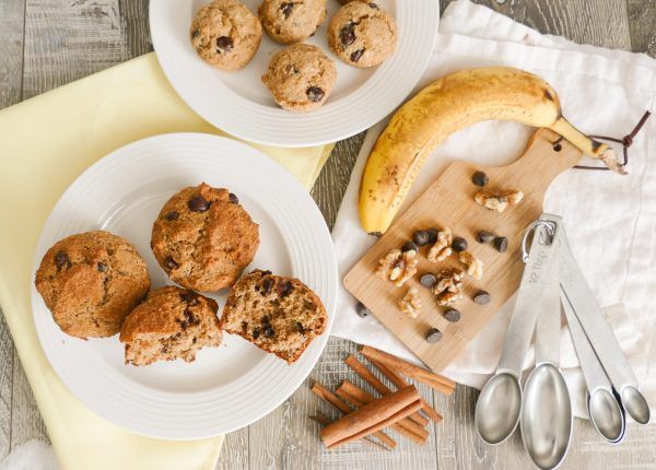 two white plates with muffins on them next to a banana and cinnamon sticks