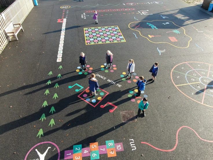 several children are playing with chalk on the pavement in an area that has various colored shapes and numbers