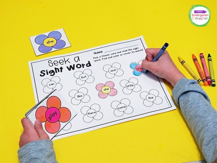 a child's hands writing on a sight word