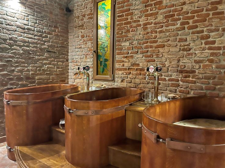 a bathroom with two large tubs next to each other in front of a brick wall