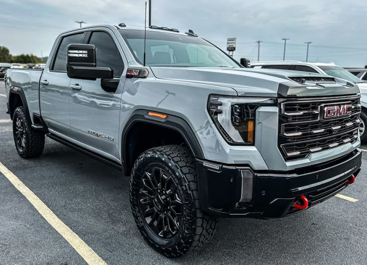 a silver truck parked in a parking lot next to other cars and trucks at a dealership