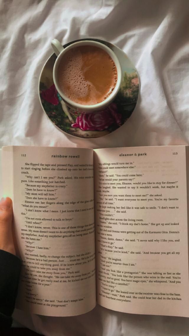 a cup of coffee and an open book on a bed