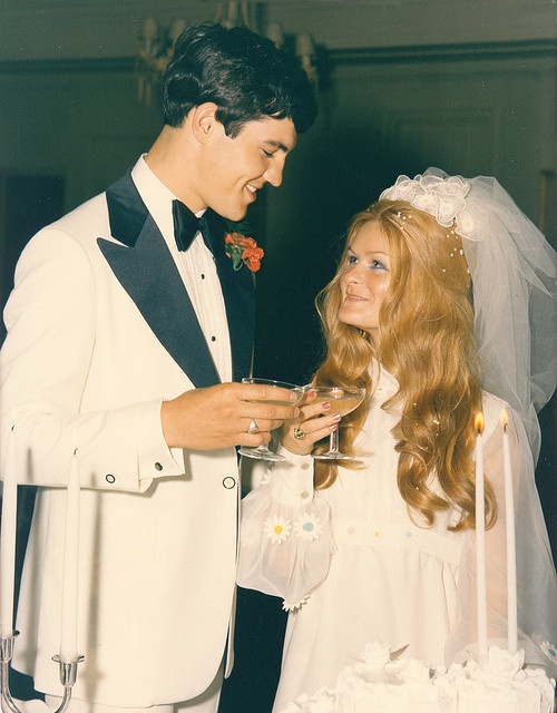 a man and woman standing next to each other in front of a cake