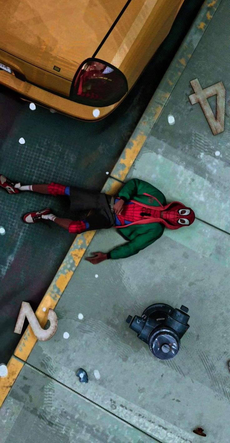 a spider - man is standing on the sidewalk next to a parking meter and car