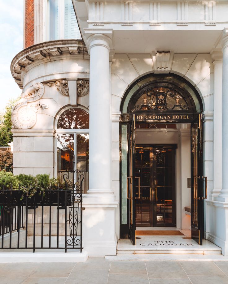 an entrance to a hotel with white columns and black wrought iron gates on the sidewalk